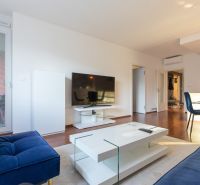 Living room in a two-room apartment with a wooden decor floor and balcony doors.