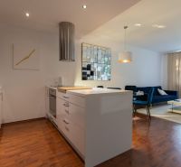 Living room with kitchen in a 2-room apartment, wooden decor flooring, white furniture.