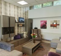 Commercial spaces with wood-patterned flooring, sofas, an armchair, and decorative cushions.