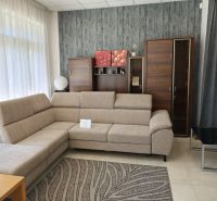 Commercial space with a beige sofa, wooden cabinet, and patterned carpet.
