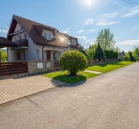 A family house in Sliač, a spacious street surrounded by green trees and a blue sky.