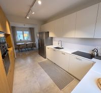 Bright kitchen and dining room in a family house with wood-patterned flooring.