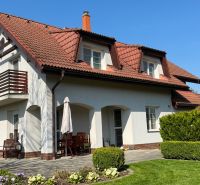 A family house in Sliač with a red roof, a balcony, and a garden with flowers.