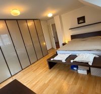A bedroom in a family house with a wooden decor floor and a large wardrobe.