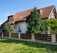 A family house in Sliač with a wooden fence and a landscaped garden.