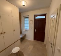 Entrance hall in a family house with white storage space and brown doors.