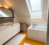Bathroom with double sink, bathtub, and decorative tiles in a family house.