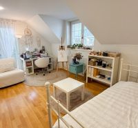 A bright bedroom in a family house with a wood-patterned floor and a writing desk.