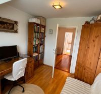 A home office in a family house with wooden decor and shelves full of books.