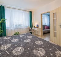 Bedroom with a dandelion-patterned bedspread, a writing desk, and a wooden decor floor.