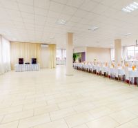 Commercial space with wood-patterned flooring, tables and chairs arranged in a row.