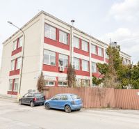 The building on Jána Zigmundíka Street in Vrbové, surrounded by cars and greenery.
