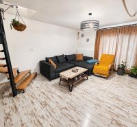 Living room in a family house with a wooden decor floor, a sofa, and stairs.