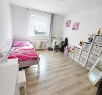 A room with a bed, a floor with a wooden decor, and decorations in a family house.