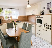 A kitchen in a family house with wooden decor, green chairs, a dining table, appliances.