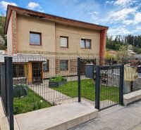 A family house in Zákopčie with a garden, lawn, and metal fence.