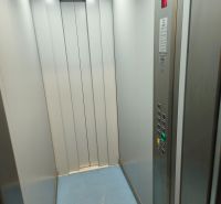 Modern elevator interior with steel walls and a simple control panel.
