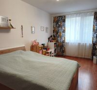 A bedroom in a 2-room apartment with a bed, decorative curtain, and floor with a wooden decor.