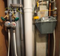 Plumbing and gas meter in a 2-room apartment with a wooden decor floor.