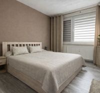 A bedroom with a bed, nightstands, and a floor with a wooden decor in a 4-room apartment.