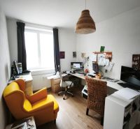 A home office with a yellow chair, wood-patterned flooring, and a large window in a 4-room apartment.