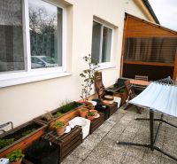 Terrace of a 4-room apartment in Malá Lehota with flower pots, plants, and garden furniture.