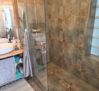 A bathroom in a 4-room apartment with a large shower and a glass screen.