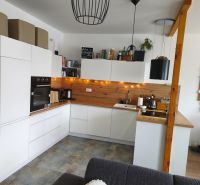 A kitchen in a 4-room apartment with white cabinets and wood decor.