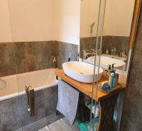 A bathroom with a wooden washbasin counter and a bathtub in a 4-room apartment.