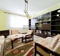 A bright living room in a two-room apartment with wooden furniture and a large bookshelf.