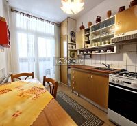 A kitchen in a 2-room apartment with a wooden decor floor and a balcony window.
