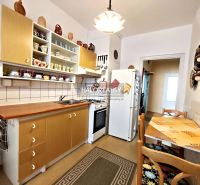 A kitchen in a 2-room apartment with wooden cabinets and a dining area.