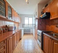 A kitchen in a 3-room apartment with wooden cabinets and a floor with a wood decor.