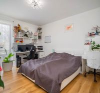 A bedroom in a family house with a desk, computer, and wooden decor flooring.
