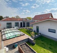 A family house in Pama with a landscaped garden, glass shelter, and lawn.