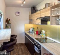 A kitchen with wooden decor, storage spaces, and a bar counter in a family house.