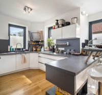 A kitchen in a family house with white furniture and a wooden decor floor.