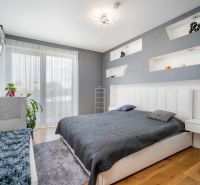 A bedroom in a family house with a wood-patterned floor, a gray wall, and a television.