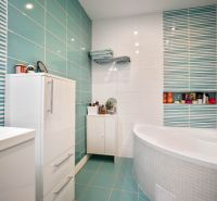 A bathroom in a family house with turquoise tiles and white furniture.