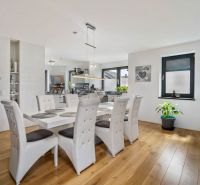 Dining room in a family house with a wooden decor floor, white chairs, and a houseplant.