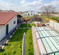A family house in Pama with a landscaped yard, a swimming pool, and a garden lined with plants.
