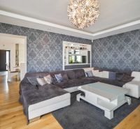 Living room in a family house with dark patterned wallpaper and a wooden decor floor.