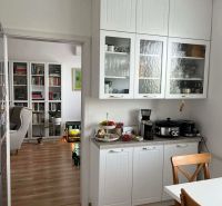 A kitchen in a 3-room apartment with white cabinets and a wood-patterned floor.