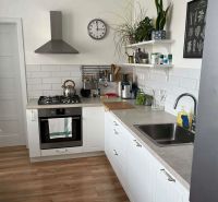 A kitchen in a 3-room apartment with white cabinets and a wooden decor floor.