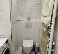 A bathroom in a 3-room apartment with a washing machine, tiles, and a wall-mounted toilet.