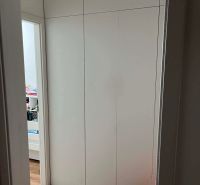 White built-in wardrobe in a 3-room apartment with a wooden decor floor.