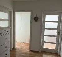Interior of a 3-room apartment with white furniture and a floor with a wooden decor.