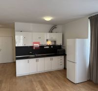 Kitchen unit with a white refrigerator and microwave oven, floor with wooden decor.