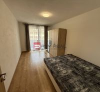 A bedroom in a two-room apartment with a wooden decor floor and a balcony.