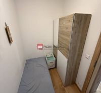 A narrow room with a bed, a wardrobe, and a floor with a wooden decor in a 2-room apartment.
